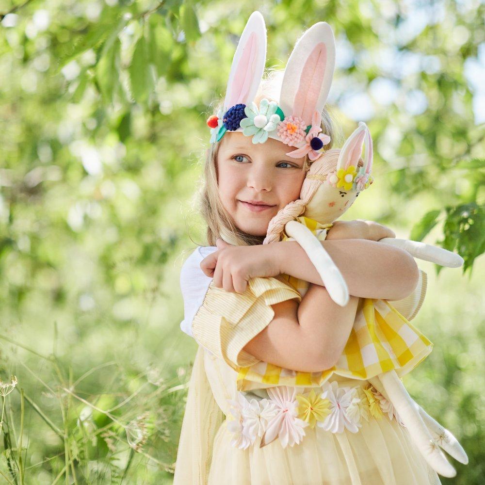 Alice is crafted from fabric, and is wearing a yellow gingham dress and a bunny ear headband. 