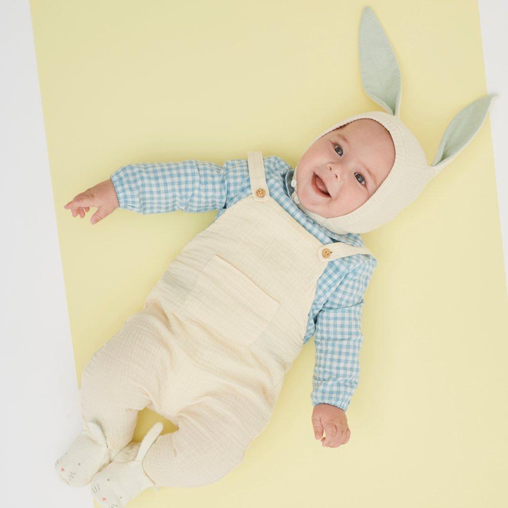 This organic cotton bunny bonnet has a shimmering peach inner on the ears, and an ivory coloured button fastening. 