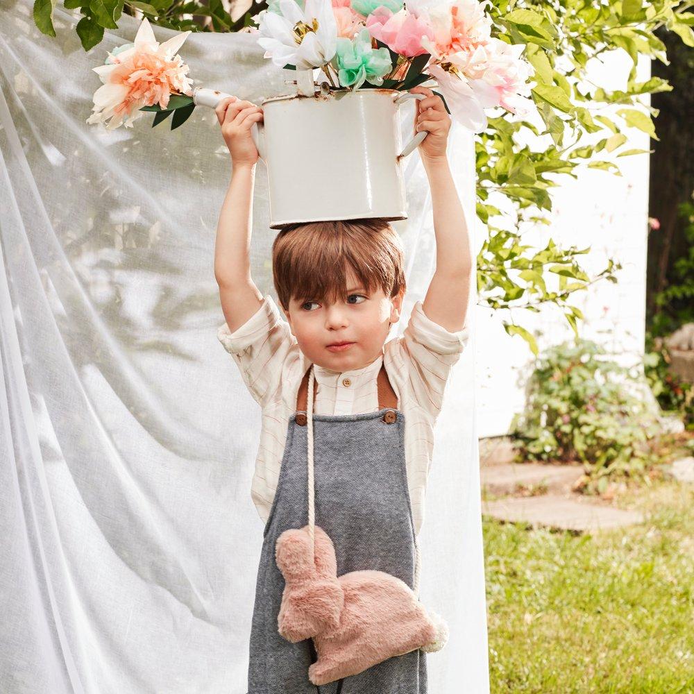 This soft bunny bag, crafted from lined dusky pink plush, has a cross body cord strap, zip closure and pompom tail detail.