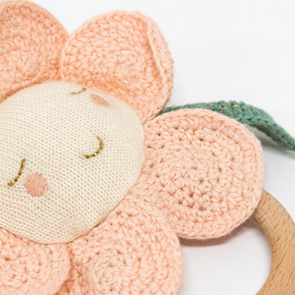 This adorable daisy baby rattle is crafted from knitted organic cotton, with a wooden grip ring and soft noise rattle