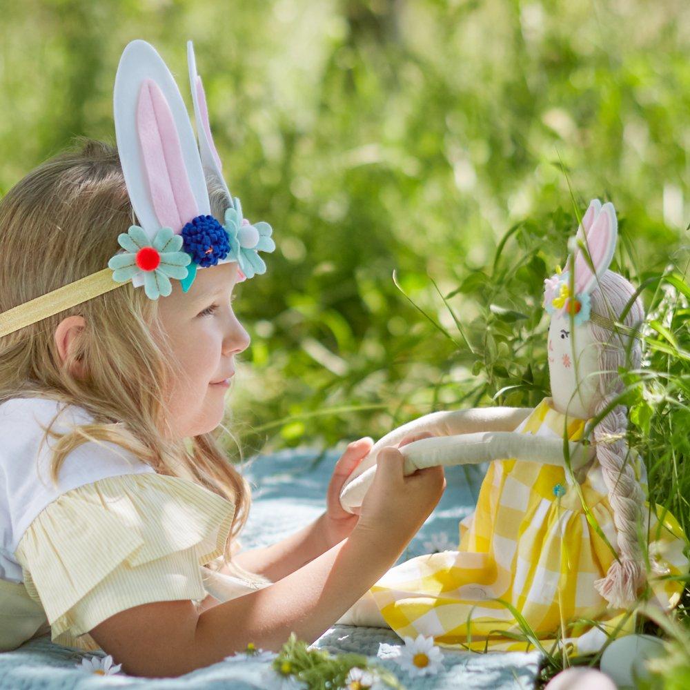 Alice is crafted from fabric, and is wearing a yellow gingham dress and a bunny ear headband. 